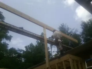 Carpenter setting a ridge beam over a new addition frame — Ice Dam Removal by Roofing Brothers in Anderson