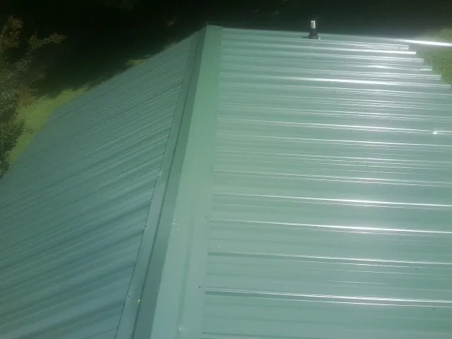 New green metal panels meeting at the ridge of a roof — Flat Roof Repair work by our crew in Anderson