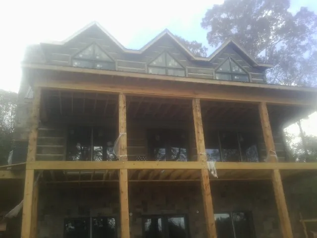 Dormers and porch framing on a large log home under construction — Roof Coating work by our crew in Anderson